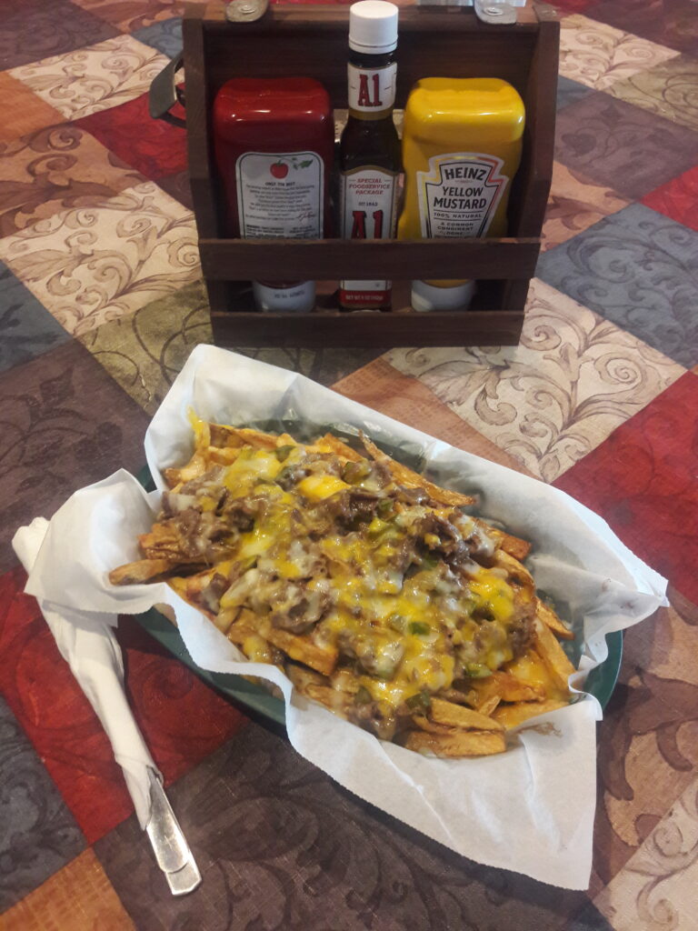 Basket of fries topped with philly meat, onions, green peppers and melted cheese