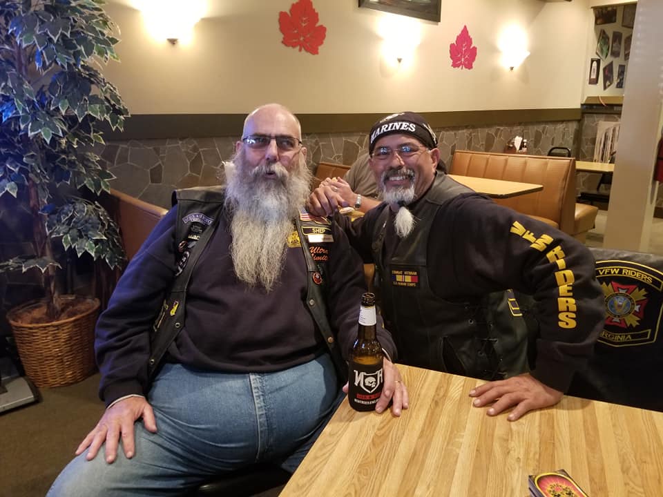 Two VFW Riders with long beards in leather vests at a table after a long motorcycle ride